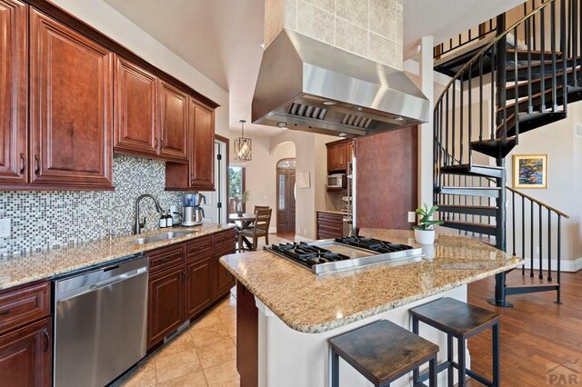 kitchen with tasteful backsplash, a sink, appliances with stainless steel finishes, a kitchen bar, and extractor fan