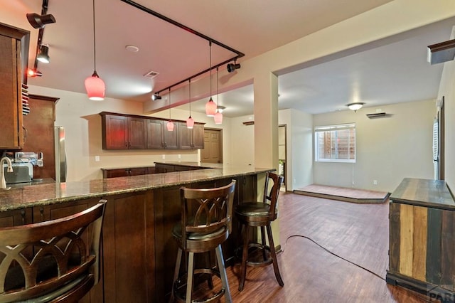 kitchen with rail lighting, hanging light fixtures, dark stone countertops, and dark wood finished floors
