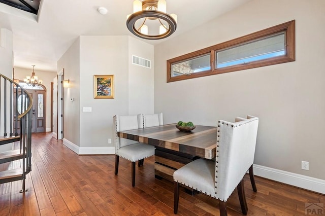 dining room featuring an inviting chandelier, visible vents, hardwood / wood-style flooring, and baseboards
