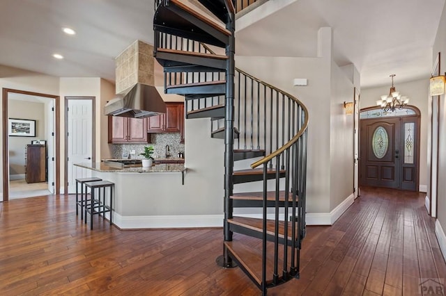 stairs with recessed lighting, an inviting chandelier, hardwood / wood-style floors, and baseboards