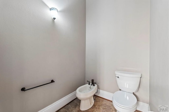 half bathroom featuring toilet, a bidet, and baseboards