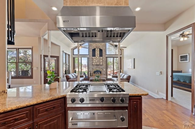 kitchen with a warming drawer, a ceiling fan, open floor plan, and range hood