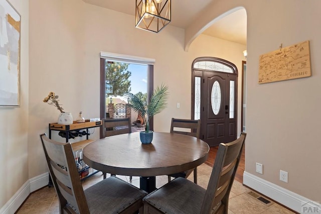 dining space with visible vents, light tile patterned floors, arched walkways, and baseboards