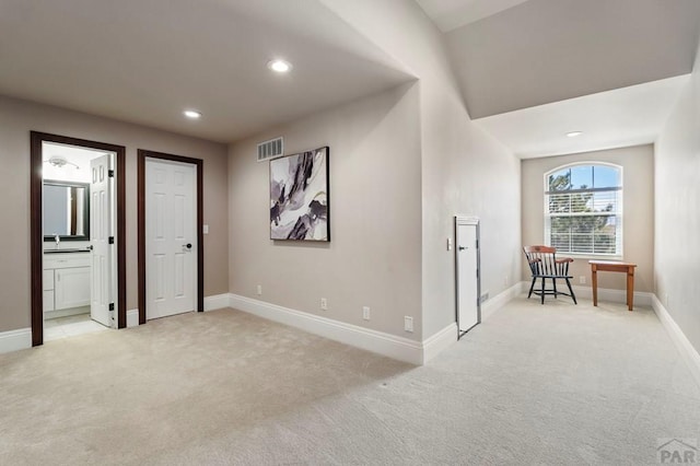 interior space featuring light colored carpet, visible vents, recessed lighting, and a sink