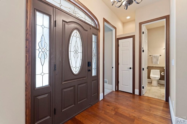 foyer entrance featuring an inviting chandelier, dark wood-style flooring, and baseboards