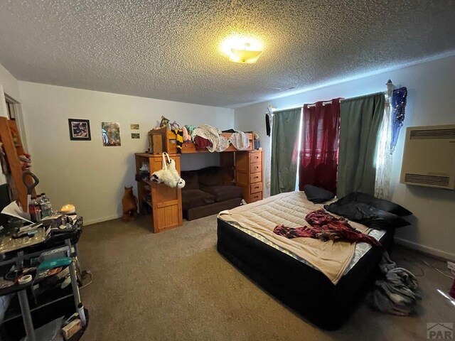 carpeted bedroom with a wall unit AC, a textured ceiling, and baseboards