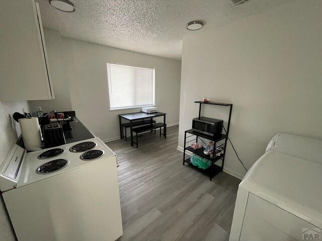 kitchen featuring a textured ceiling, light wood-type flooring, white electric range oven, and baseboards