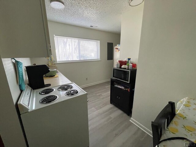 kitchen with a textured ceiling, baseboards, light wood-type flooring, stainless steel microwave, and white electric range oven