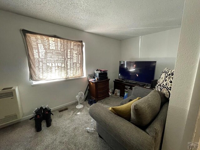 interior space featuring baseboards, visible vents, heating unit, a textured ceiling, and carpet floors