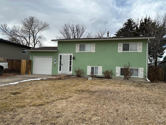 view of front of property with a garage, driveway, fence, a front lawn, and stucco siding