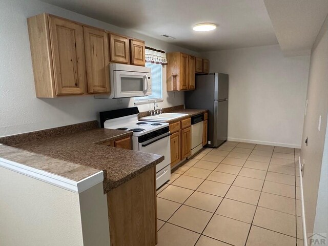 kitchen featuring dark countertops, a peninsula, stainless steel appliances, open shelves, and a sink