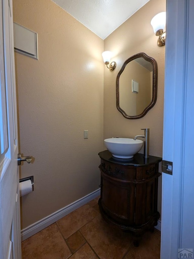 half bathroom featuring tile patterned flooring, vanity, and baseboards