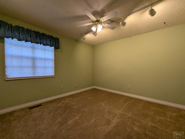 carpeted empty room with a textured ceiling, ceiling fan, visible vents, and baseboards