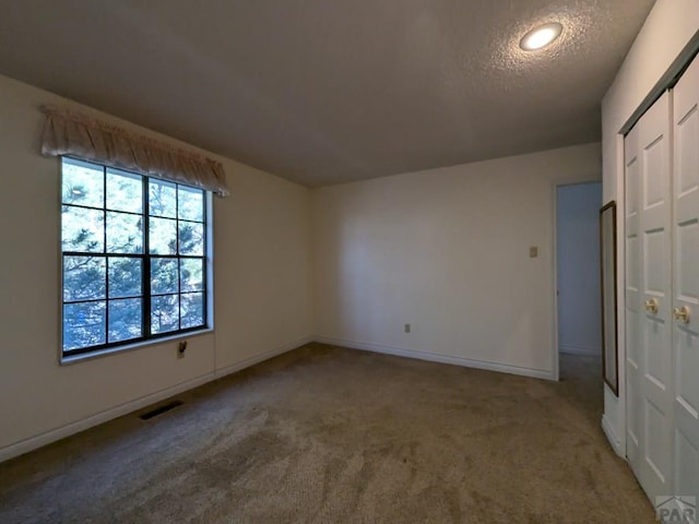 unfurnished bedroom featuring a closet, visible vents, a textured ceiling, and carpet flooring