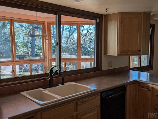 kitchen with a wealth of natural light, dark countertops, dishwasher, and a sink