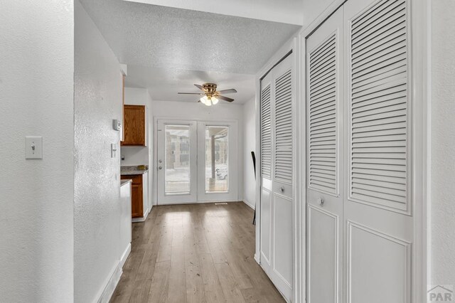 interior space featuring light wood-type flooring, baseboards, a textured ceiling, and a textured wall