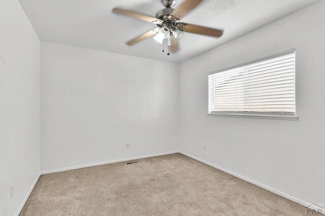 empty room with light carpet, ceiling fan, visible vents, and baseboards