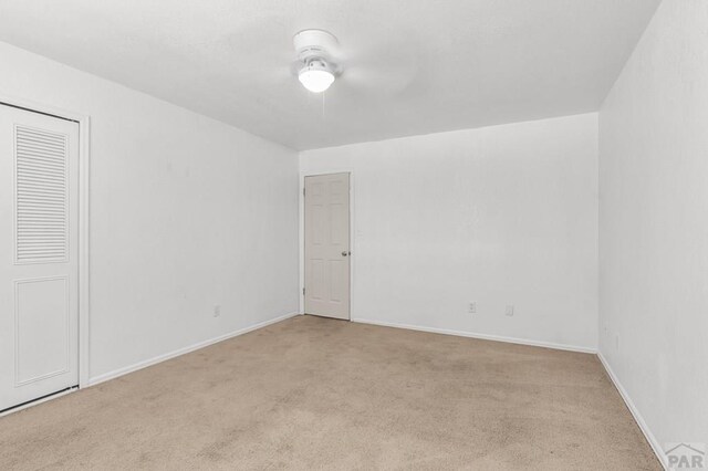 empty room featuring baseboards, a ceiling fan, and light colored carpet