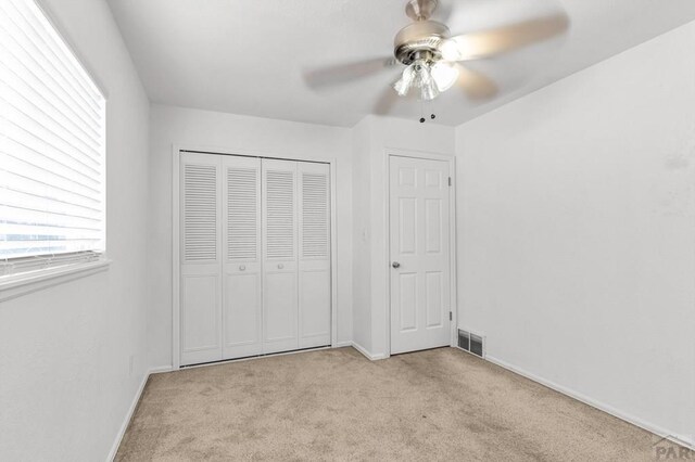 unfurnished bedroom with light carpet, baseboards, visible vents, ceiling fan, and a closet