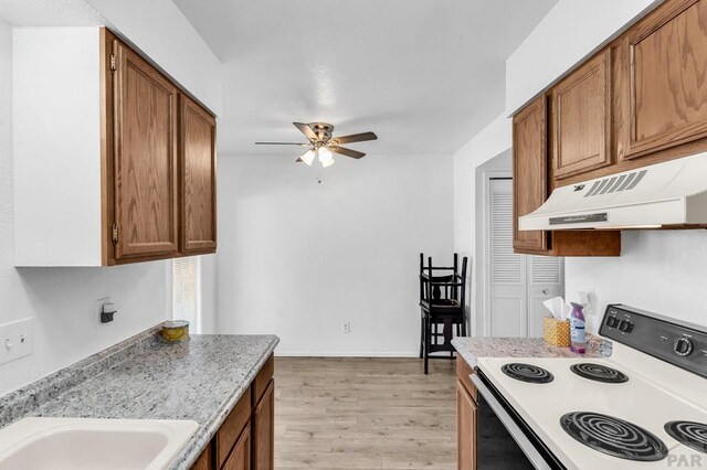 kitchen featuring brown cabinetry, range with electric cooktop, light wood-style floors, and under cabinet range hood