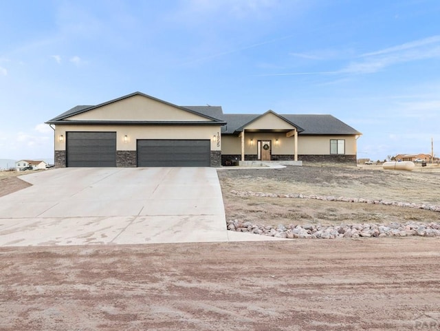 1855 N Buckboard Ave, Pueblo West, CO 81007 - view of front of property with an attached garage, concrete driveway, stucco siding, and stone siding