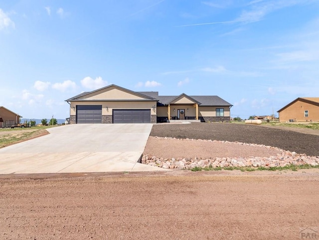 1855 N Buckboard Ave, Pueblo West, CO 81007 - view of front facade featuring concrete driveway, an attached garage, and stone siding