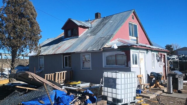 rear view of house featuring metal roof and a chimney