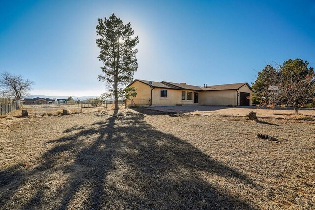 rear view of house with fence and an attached garage