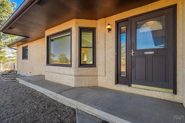 view of exterior entry with visible vents and stucco siding