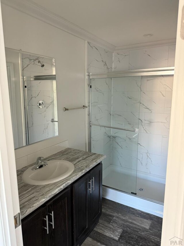 bathroom with ornamental molding, a marble finish shower, and vanity