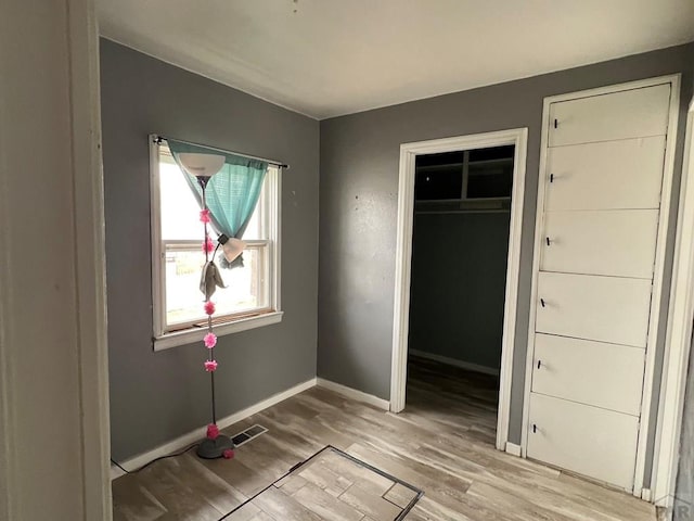 unfurnished bedroom featuring a closet, baseboards, visible vents, and light wood finished floors