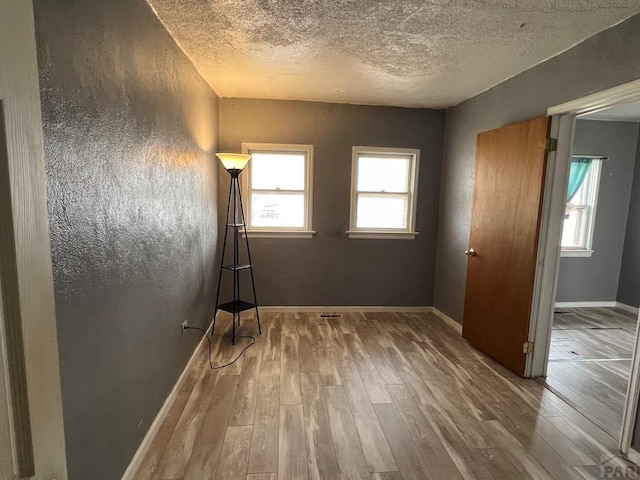 unfurnished bedroom featuring wood finished floors, baseboards, and a textured ceiling