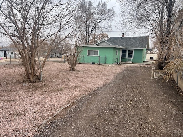 view of front of property with fence, a chimney, roof with shingles, and stucco siding