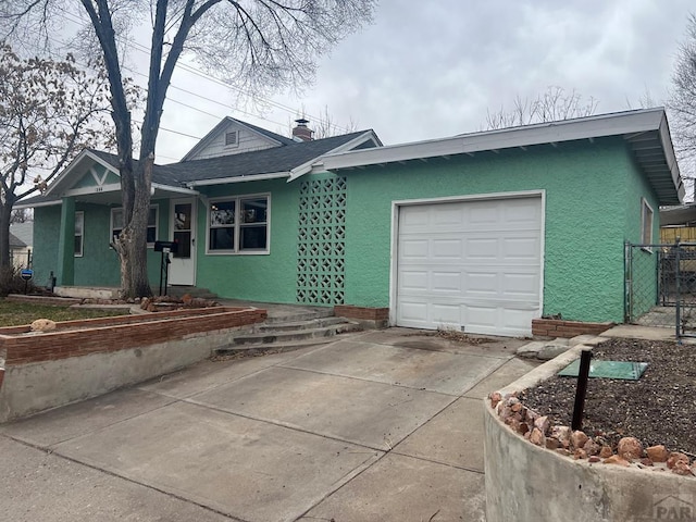 ranch-style home with stucco siding, an attached garage, driveway, and fence