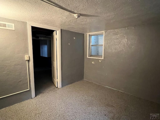 unfurnished room featuring visible vents, carpet floors, a textured ceiling, and a textured wall