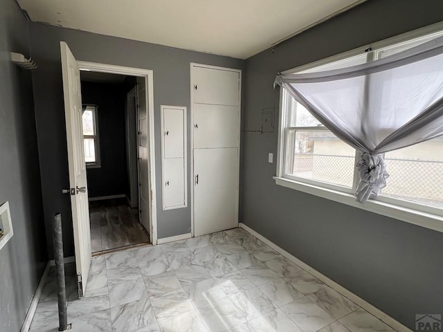 unfurnished bedroom featuring a closet, marble finish floor, and baseboards