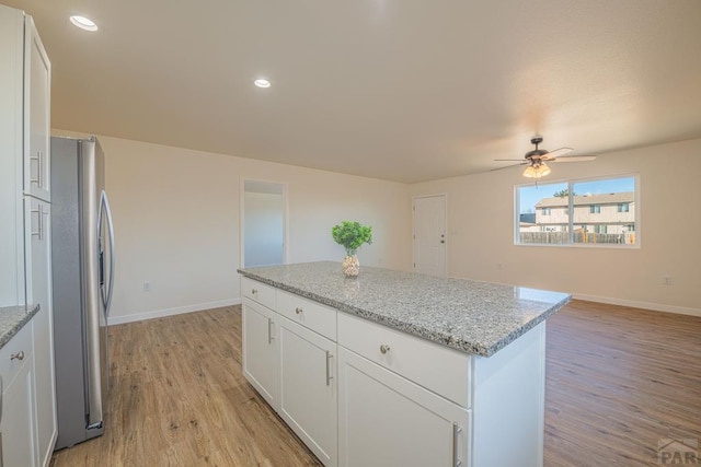 kitchen featuring light wood-type flooring, stainless steel refrigerator with ice dispenser, white cabinetry, and a center island