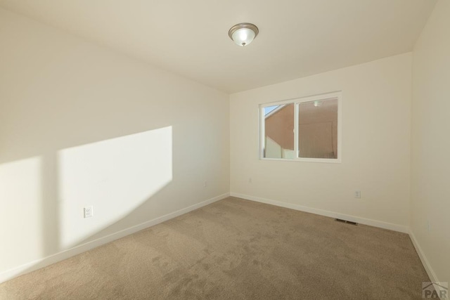 spare room featuring visible vents, baseboards, and carpet flooring