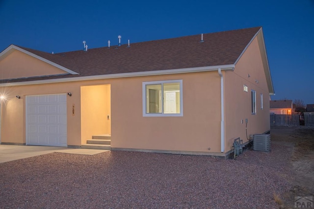 view of front facade featuring a garage, central air condition unit, concrete driveway, and stucco siding