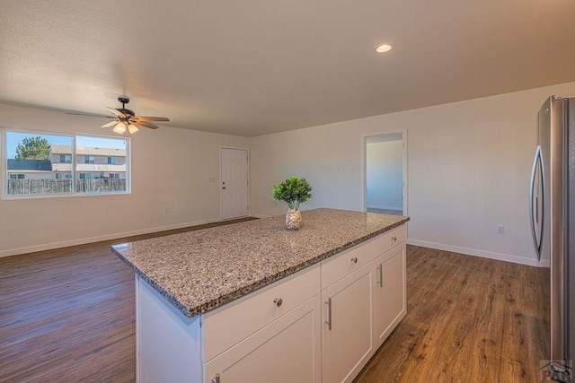 kitchen featuring baseboards, dark wood-style floors, freestanding refrigerator, light stone countertops, and white cabinetry