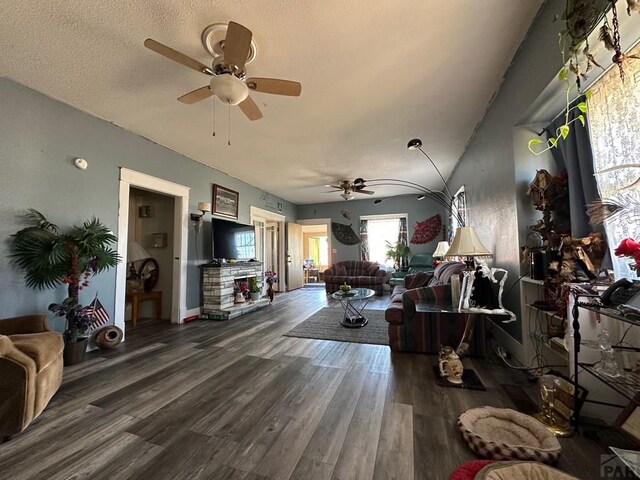 living room with a textured ceiling, a ceiling fan, and wood finished floors