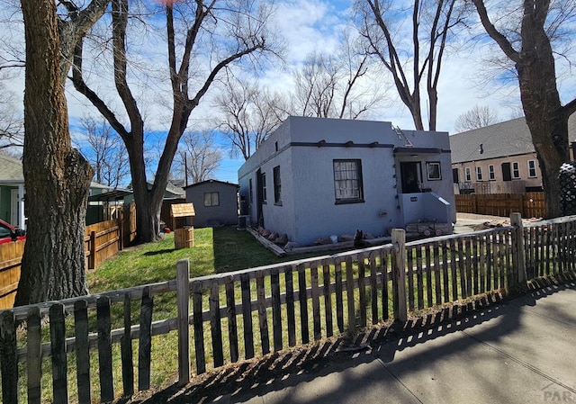 view of front of home with stucco siding, a fenced front yard, and a front lawn