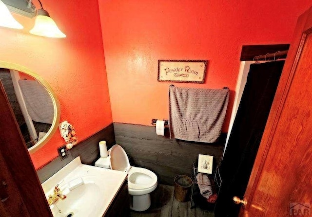 bathroom with toilet, vanity, and wainscoting