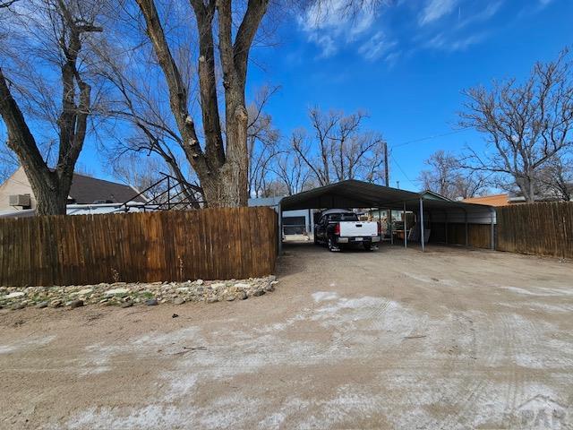 view of parking / parking lot with a detached carport, driveway, and fence