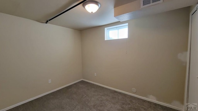 below grade area with baseboards, visible vents, and dark colored carpet