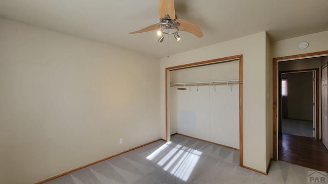 unfurnished bedroom with a closet, light colored carpet, ceiling fan, and baseboards