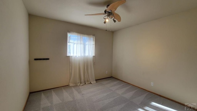 unfurnished room with light carpet, baseboards, and a ceiling fan