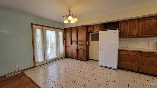 kitchen featuring visible vents, light countertops, hanging light fixtures, freestanding refrigerator, and an inviting chandelier