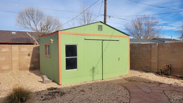 view of outbuilding with a fenced backyard and an outbuilding