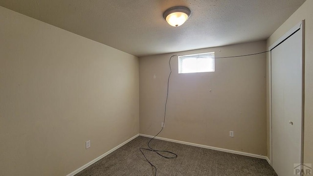 below grade area featuring a textured ceiling, carpet floors, and baseboards